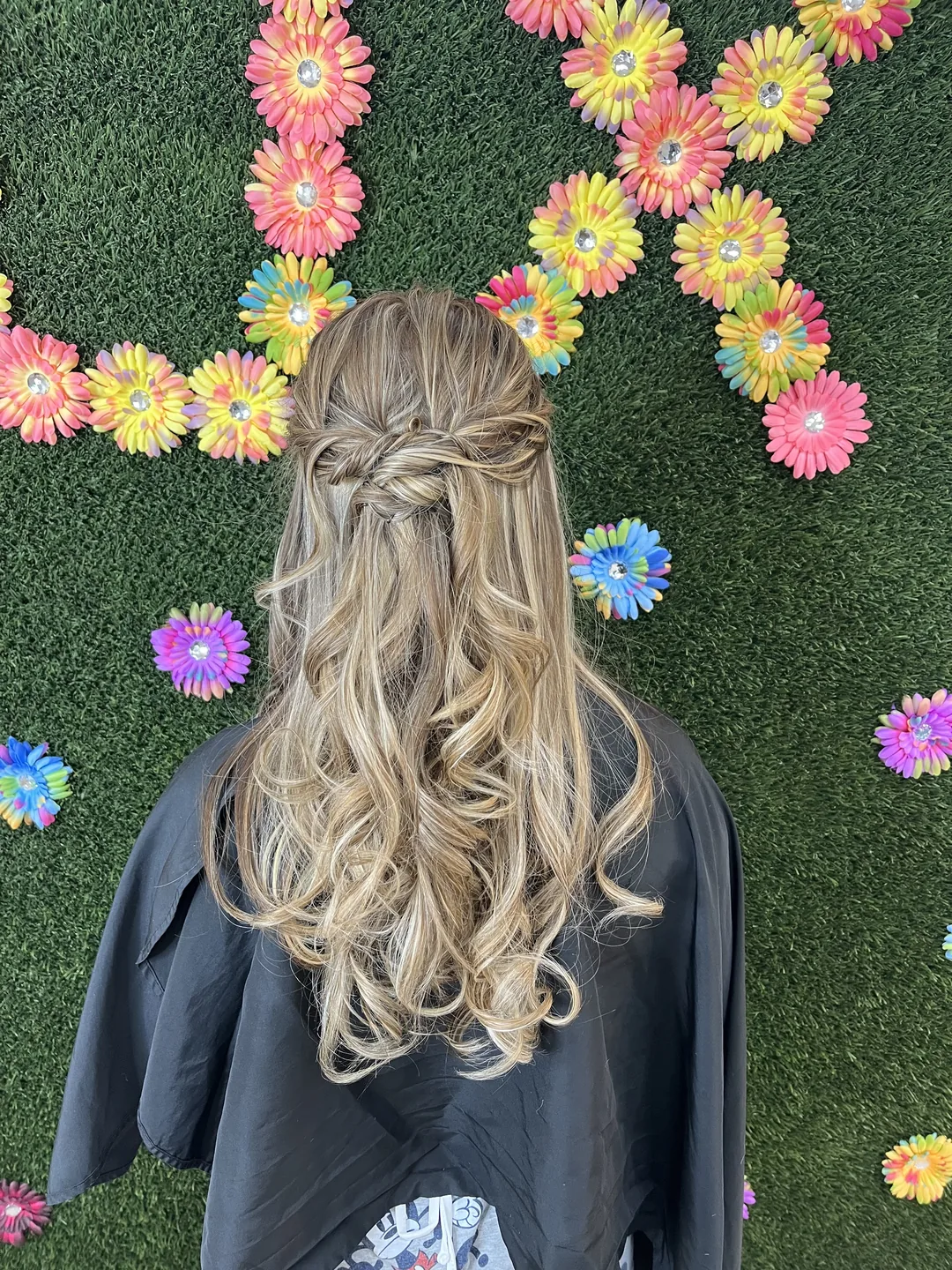 half-up braid with curls against floral wall