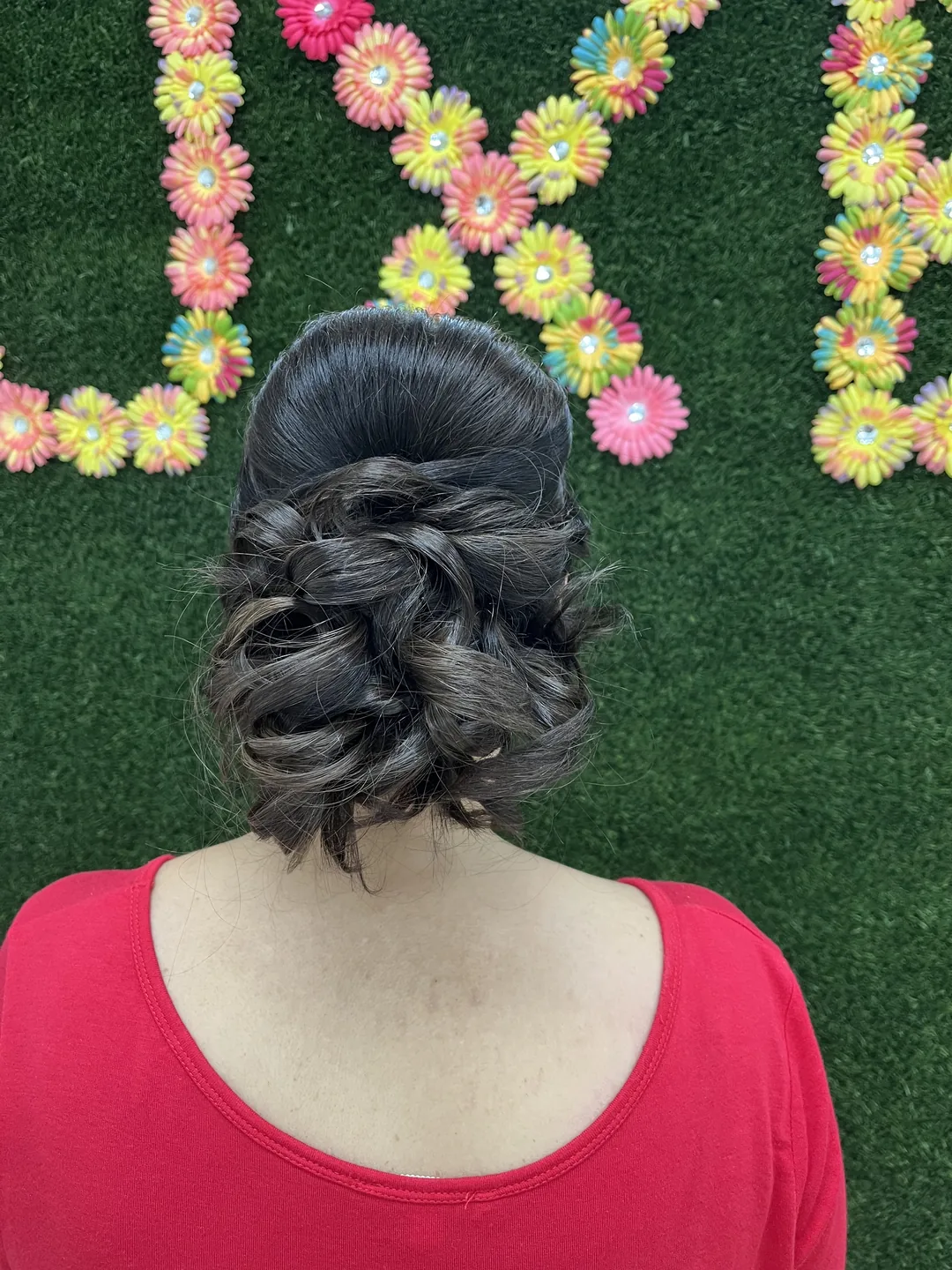 low-bun braided updo against floral LUXE wall